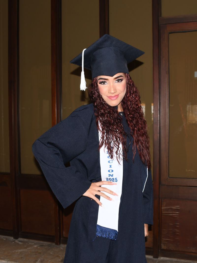 Graduada del CEAC con toga y birrete en el pasillo del salón de ceremonias