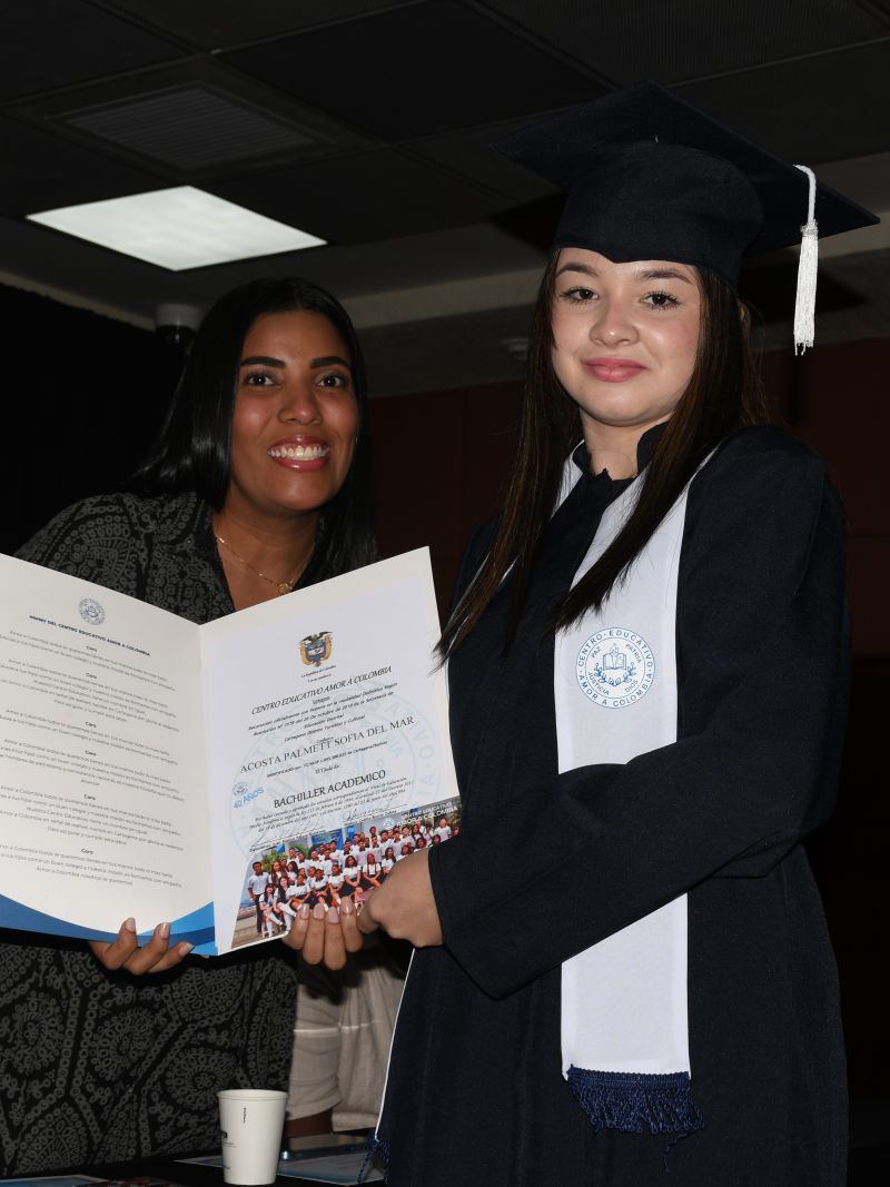 Graduada recibiendo su diploma de una docente durante la ceremonia