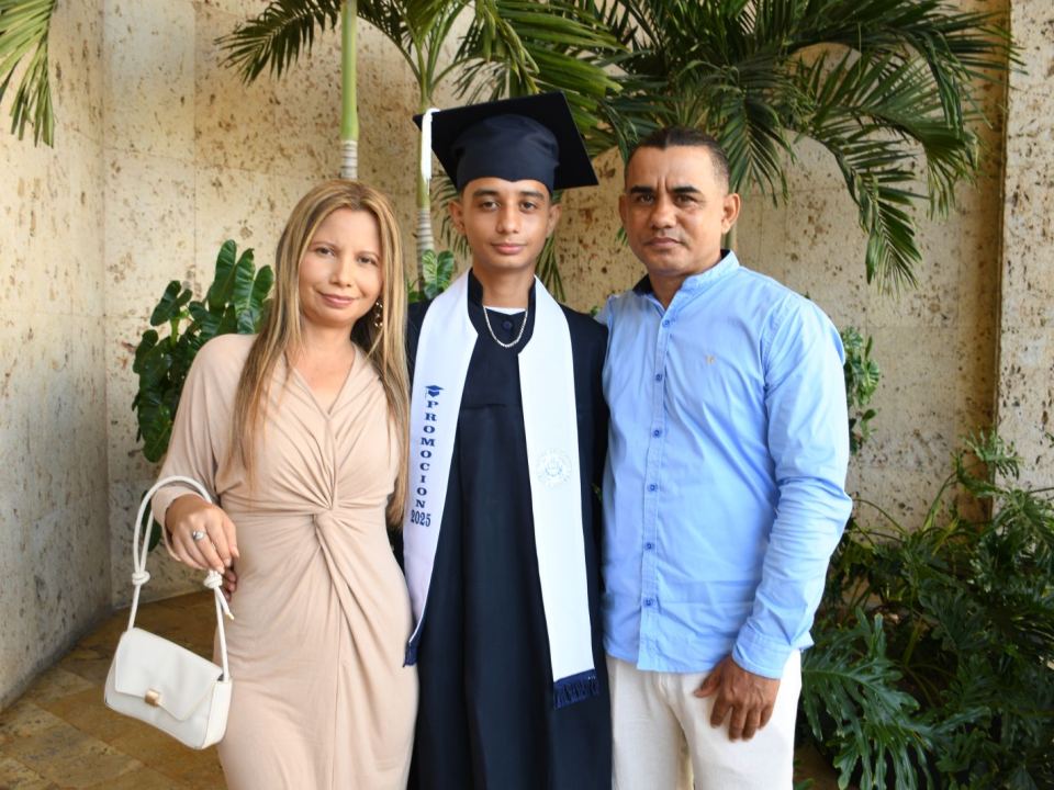 Graduado del CEAC con birrete y banda de la Promoción 2025, abrazado por su mamá y su papá